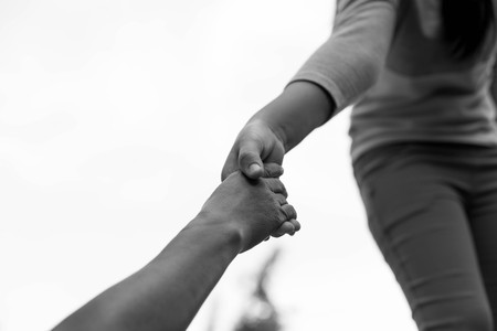 Help Concept Young girl Hands reaching out to help old woman in black and whiteの写真素材
