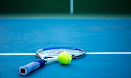 Tennis ball and racket on tennis court with white lineの写真素材