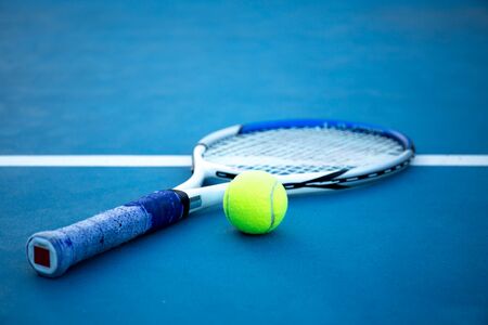 Tennis ball and racket on tennis court with white lineの写真素材