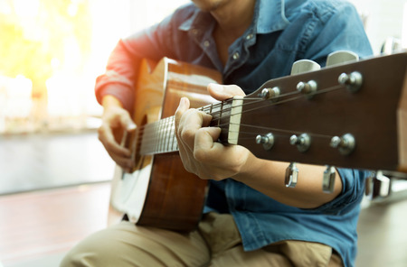 Man playing acoustic guitar with light flare in backgroundの写真素材