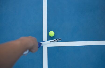 Tennis racket and tennis ball on blue court with white lineの写真素材