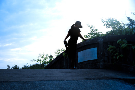 Unidentified jogger stretching on bridge in silhouetteの写真素材