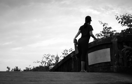 Unidentified woman jogger stretching on bridge in black and whiteの写真素材