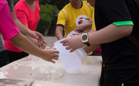 Volunteer people pouring water for athletes marathon runner at service pointの写真素材