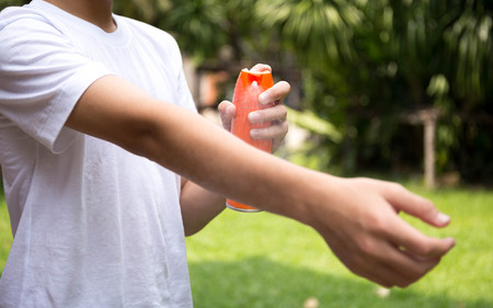 Young boy spraying insect repellents on skin in the garden with spray bottleの写真素材