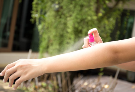 Woman spraying insect repellents on skin in the garden with spray bottleの写真素材
