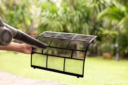 Technician man dry up and dust cleaning air Conditioner filter with electric blowers outside