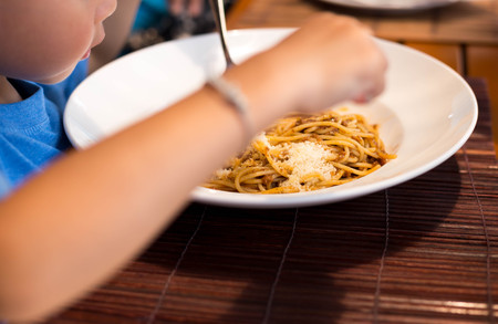 Selected focus little child enjoy eating spaghetti with bolognese at lunch timeの写真素材