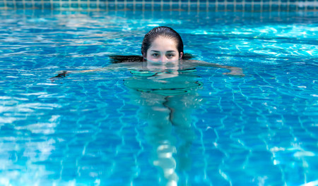 Girl half face in the swimming pool looking at the camera in vacation