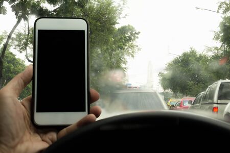 Safty concept Man driving using cell phone while raining in bad trafficの写真素材