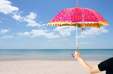 Woman holding colorful umbrella on the beach blue sky in summer timeの写真素材