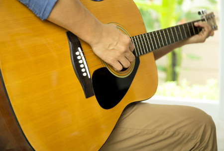 Selected focus man playing acoustic guitar indoorsの写真素材