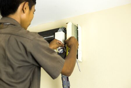 Electrician repairman fixing air conditioning in the  houseの写真素材