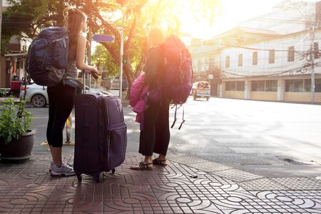 Young couple of woman with a travel bag standing on street on vacationの写真素材