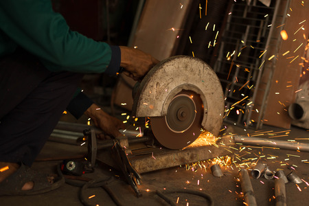 Worker use Electric grinder cutting metal with sparks in workshopの写真素材