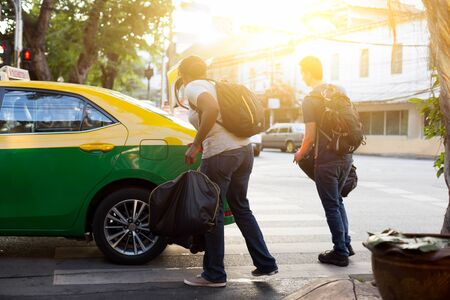 Unidentified couple with a travel bag getting in a taxi vacation in Thailandの写真素材