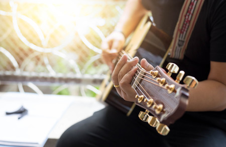 Man Practicing in playing acoustic guitar in blur backgroundの写真素材