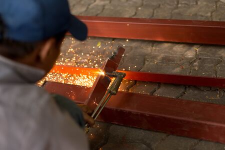 Man using torch cut metal plate in workshop