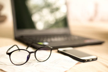 Glasses with bank statement and cell phone and laptop in the backgroundの写真素材