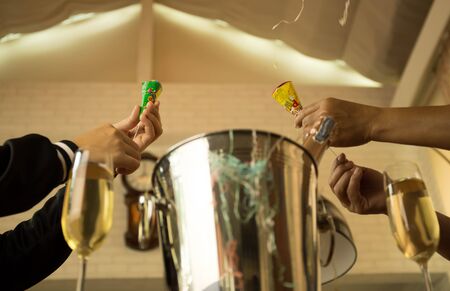Celebration Hands pulling a Christmas and New year pop up cracker with champagne glassesの写真素材