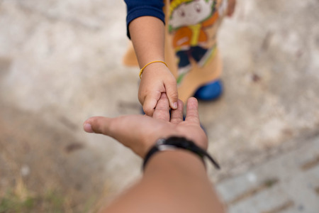 Little child holding her father is hand while walkingの写真素材