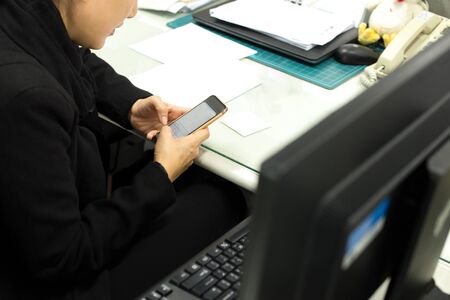 Selected focus on cell phone Candid image of  business woman used cell phone texting for working in the officeの写真素材