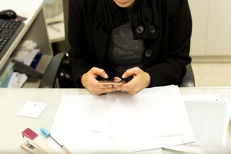Selected focus on cell phone Candid image of  business woman using cell phone working in an officeの写真素材