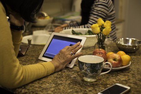 Senior woman using notepad and having cup of teaの写真素材