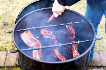 Man roasted barbecue smoke spare ribs in 200 liter fuel tankの写真素材