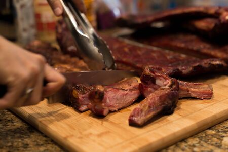 Man cutting barbecue ribs on wooden boardの写真素材
