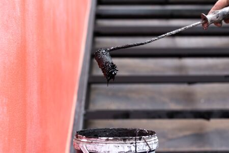 man hand holding paint roller and a bucket of black color paintの写真素材