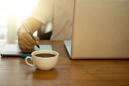 Focus on Cup of coffee businessman working with generic design notebook