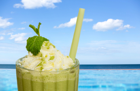 Glass of iced tea frappe drink by swimming pool with beach as backgroundの写真素材
