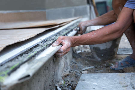 Man shape the edge of the floor with plasterer concrete cement on construction siteの写真素材