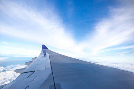 Airplane wing flying above the cloud in blue skyの写真素材