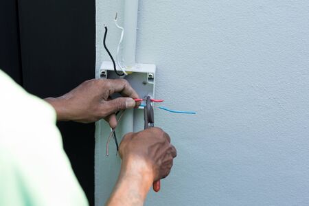 Electrician hands with pliers wires for insulationの写真素材