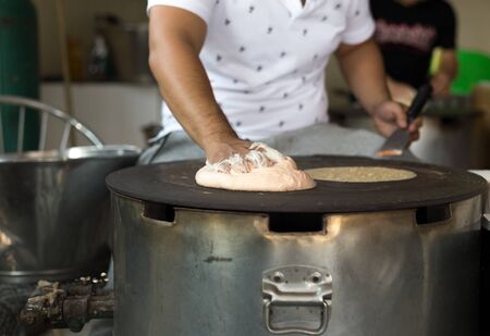 Man making a Roti dough sheet on a hot panの写真素材