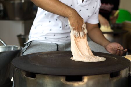 Man making a Roti dough sheet on a hot panの写真素材