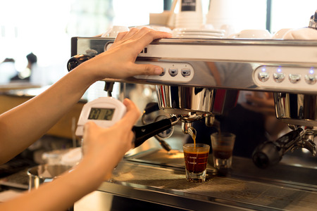 Barista making fresh espresso shot from coffee machine and stopwatch in his handの写真素材