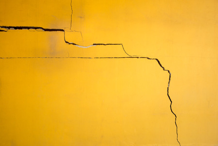 Broken yellow color concrete wall with cracked