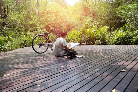Artist sketching nature on drawing board with bicycle on the sideの写真素材