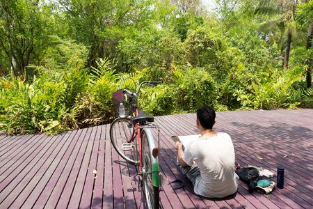 Artist sketching nature on drawing board with bicycle on the sideの写真素材