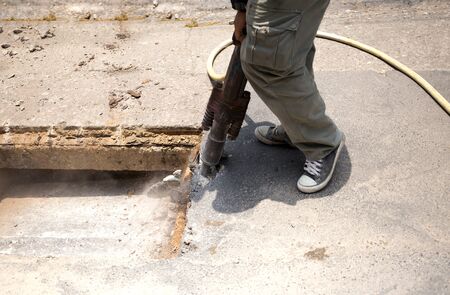 Worker working on the road site demolishing asphalt with pneumatic plugger hammerの写真素材