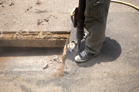 Worker working on the road site demolishing asphalt with pneumatic plugger hammerの写真素材