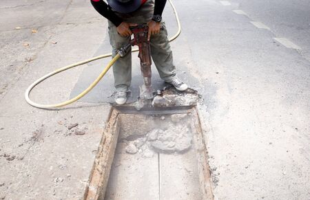 Worker working on the road site demolishing asphalt with pneumatic plugger hammerの写真素材