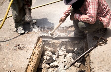 Worker working on the road site demolishing asphalt with pneumatic plugger hammerの写真素材