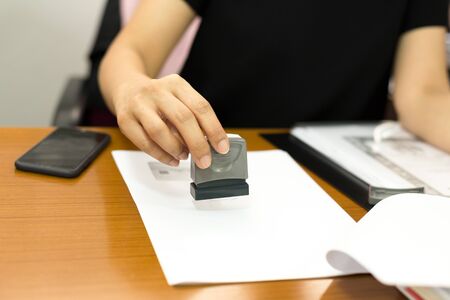 Business woman hand stamping approved document contract in office
