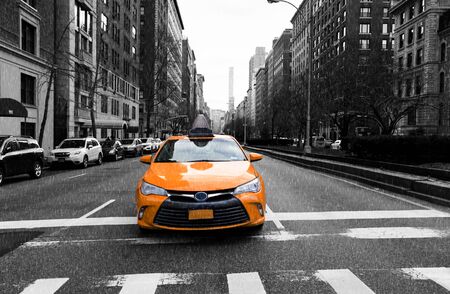 Yellow taxi in New York City sit in traffic light in the rain with building in backgroundのeditorial素材