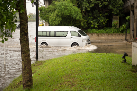 Van driving through flood water on the road during monsoon seasonの写真素材