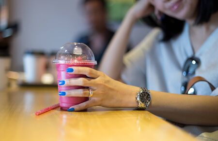 Woman hand holding mixed berry smoothie juice with nails fashion blue color in cafe shopの写真素材